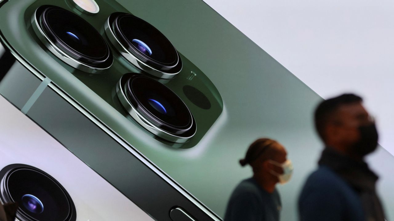 Customers walk past a digital display of the new green iPhone 13 Pro inside the Apple Store on 5th Avenue in Manhattan, New York, on March 18, 2022. 